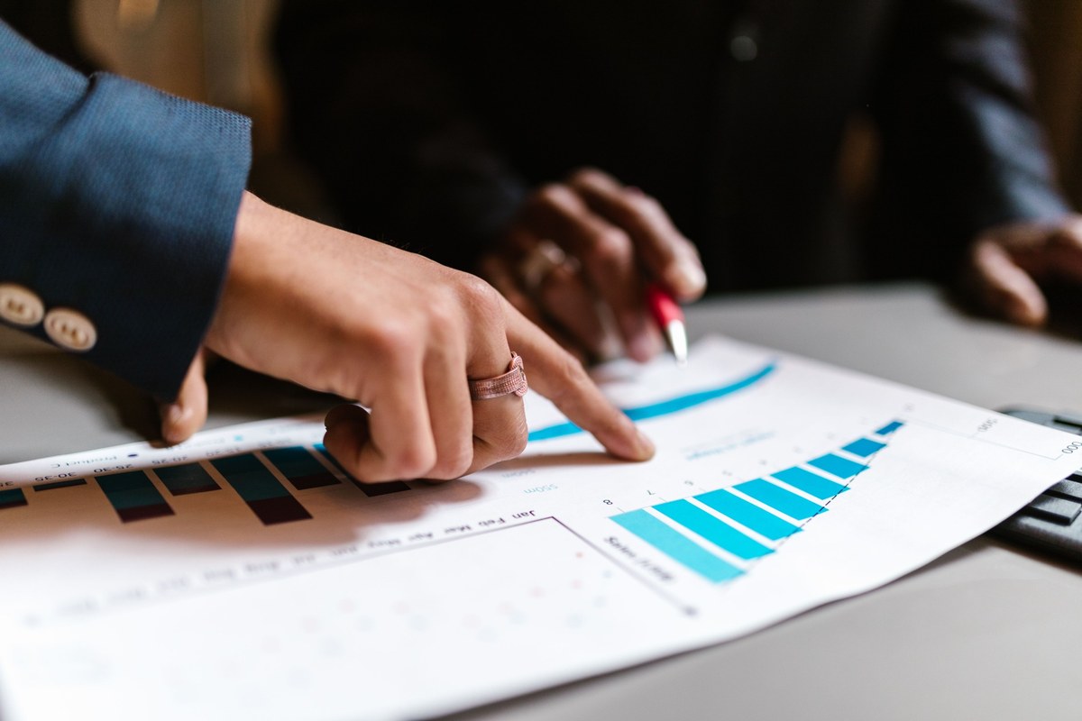 Close-up of two people reviewing financial charts and graphs on a desk, illustrating mortgage rate trends, housing market data, and buyer demand analysis.