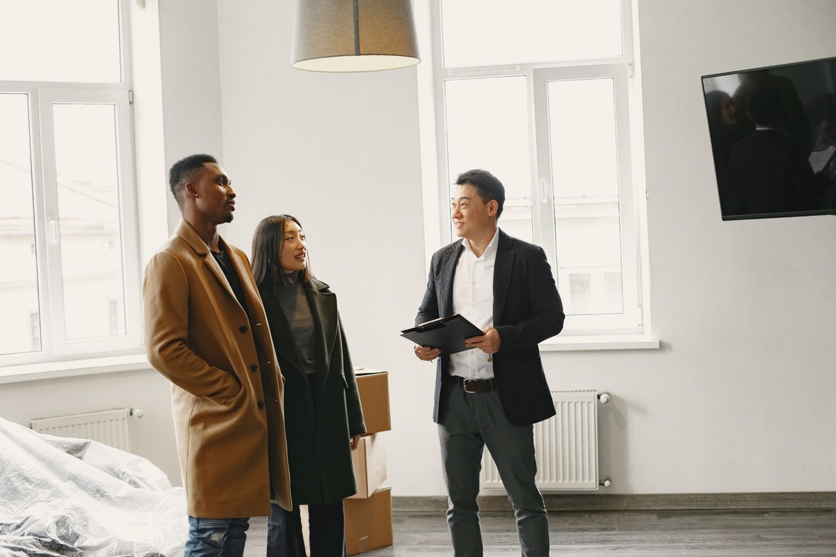 Prospective homebuyers meet with a real estate professional during a home tour, discussing the property as they explore the interior of a modern residence.