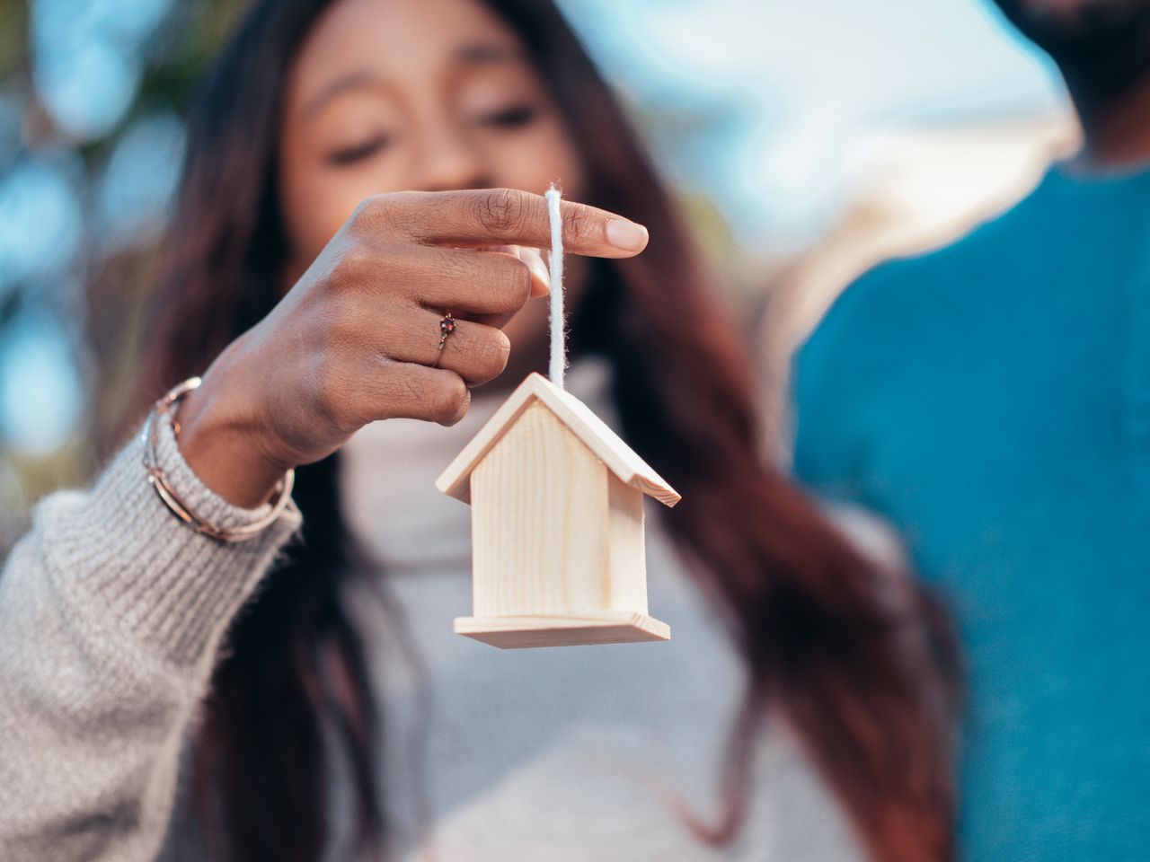 Prospective homebuyer holding a miniature wooden house.