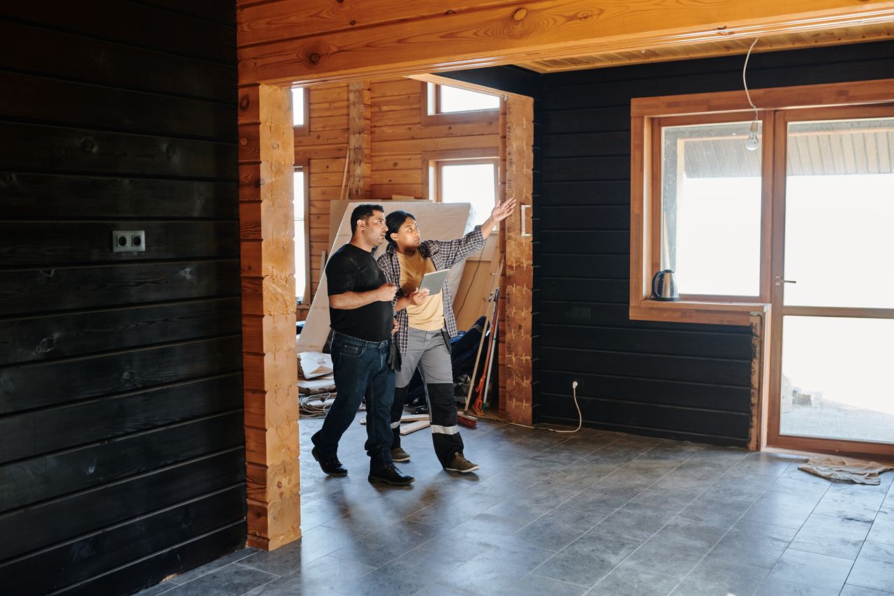 Two people discussing renovation work inside a partially finished home
